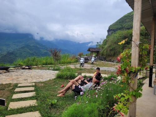 a group of people sitting in the grass with mountains in the background at Du peak home in Làng Cac