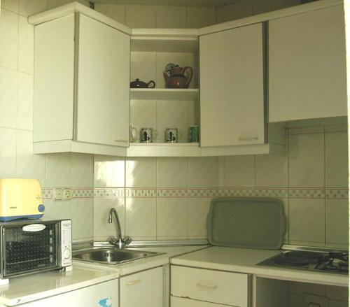 a kitchen with white cabinets and a sink and a microwave at Apartamentos Torre Levante - Arca Rent in Benidorm