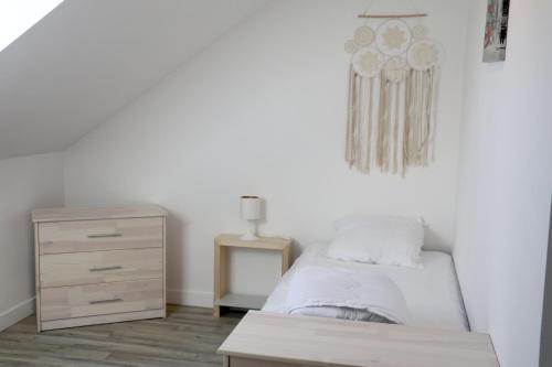 a white bedroom with a bed and a dresser at Le Logis de Laura in Trémont