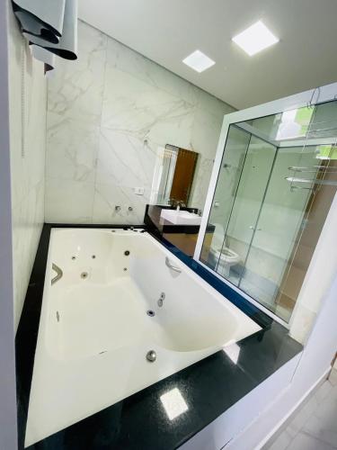 a white bath tub in a bathroom with a window at Casa com piscina e hidromassagem praia Enseada. in Guarujá