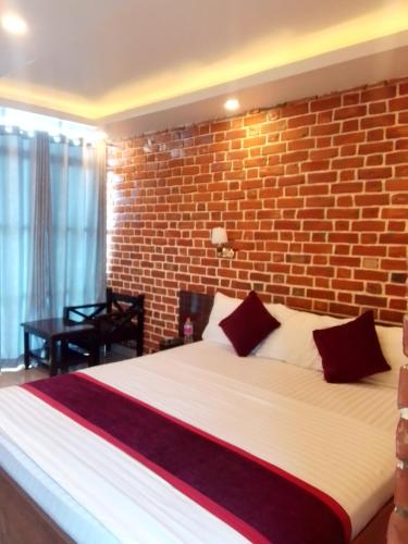 a bedroom with a large bed with a brick wall at Dhikidada Resort in Pokhara