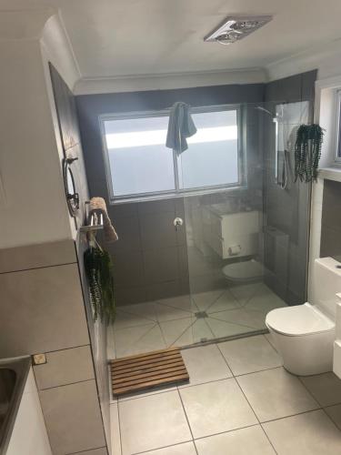 a bathroom with a shower and a toilet and a window at Sapphire Lodge in Bermagui