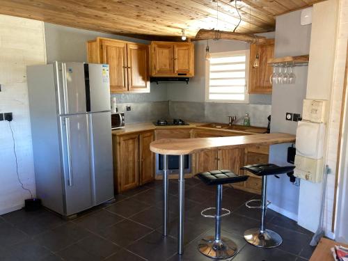 eine Küche mit einem Kühlschrank und einer Theke mit Stühlen in der Unterkunft Le Chalet de cyprès in Saint-Louis
