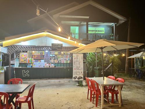 a restaurant with tables and chairs and an umbrella at Perhentian Mama's in Perhentian Island