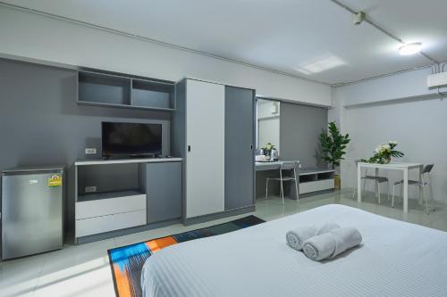 a bedroom with a bed and a television and a table at The Trust Ville in Bangkok