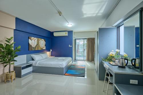 a bedroom with blue walls and a bed and a desk at The Trust Ville in Bangkok