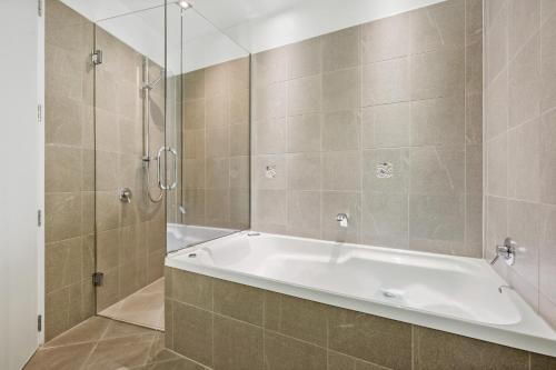 La salle de bains est pourvue d'une baignoire et d'une douche. dans l'établissement Village Lake Apartments, à Hanmer Springs