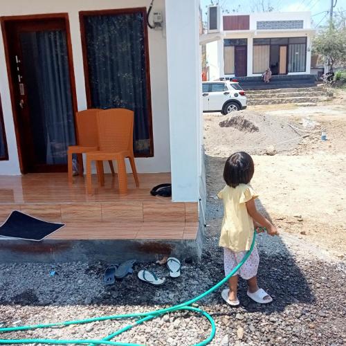 a little girl with a h hose in front of a house at The GARE'S VILLA MANDALIKA in Kuta Lombok