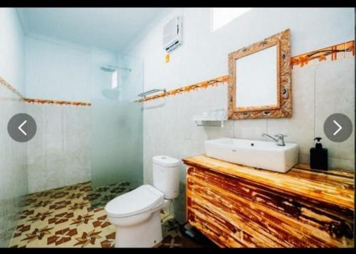 ein Badezimmer mit einem WC, einem Waschbecken und einem Spiegel in der Unterkunft Tinggian Hill Retreat in Nusa Penida