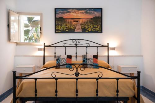 ein Schlafzimmer mit einem Bett mit einem Bild an der Wand in der Unterkunft Villa la Giara in Castellammare del Golfo