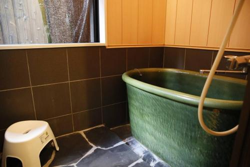 a green bath tub in a bathroom with a toilet at Kyokoi Toujimikuni in Kyoto
