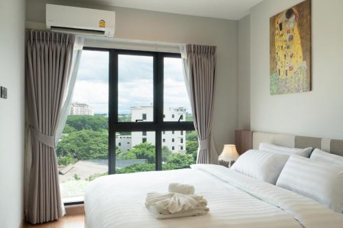 une chambre avec un lit blanc avec une grande fenêtre dans l'établissement Sky River, Luxury Infinity, Center Chiang Mai, à Chiang Mai