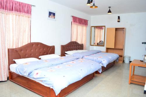 two twin beds in a bedroom with a mirror at Hill Heaven Home Stay in Kodaikānāl
