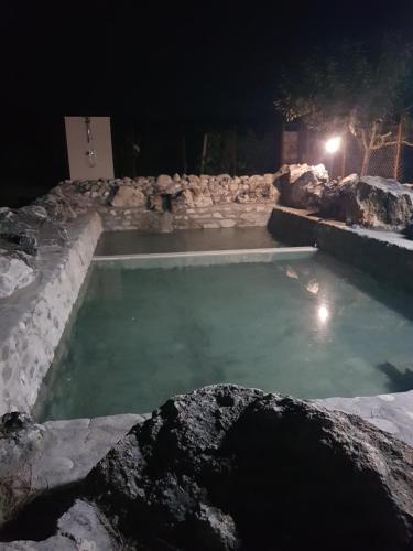a swimming pool at night with a stone wall at Wine Boutique Complex ,,Hrisimov" in Musomishta