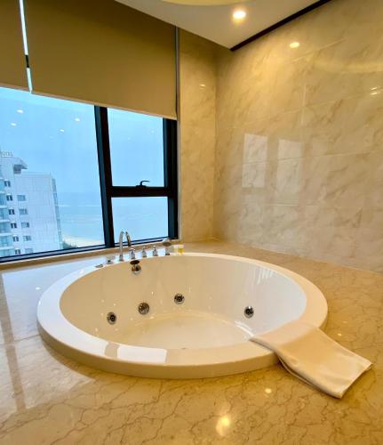 a large white tub in a bathroom with large windows at Muong Thanh Luxury Nhat Le Hotel in Dong Hoi