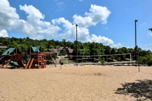 a playground with a volley ball net in the sand at Rest Haven in Branson West