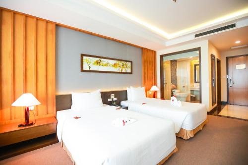 a hotel room with two beds and a bathroom at Muong Thanh Luxury Nhat Le Hotel in Dong Hoi