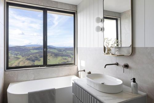 uma casa de banho com um lavatório e uma grande janela em The Bella Vista by Mt Bellevue em Myrrhee