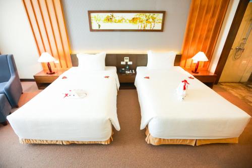 two beds in a hotel room with white sheets at Muong Thanh Luxury Nhat Le Hotel in Dong Hoi