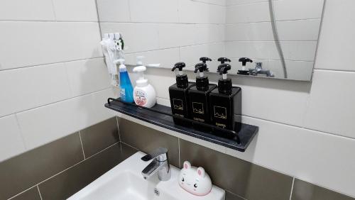 a bathroom with a sink and some bottles on a shelf at Sometimes Jeju in Jeju