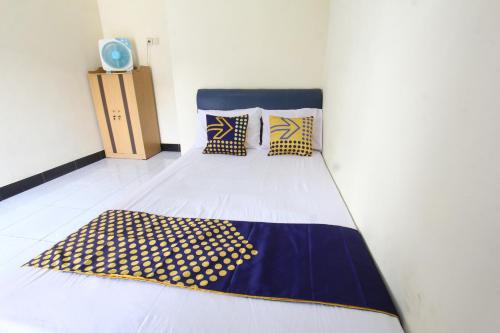 een slaapkamer met een bed met een blauwe en gele deken bij OYO Life 93157 Kos Kaloka in Tanjung