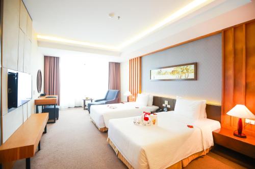 a hotel room with two beds and a television at Muong Thanh Luxury Nhat Le Hotel in Dong Hoi