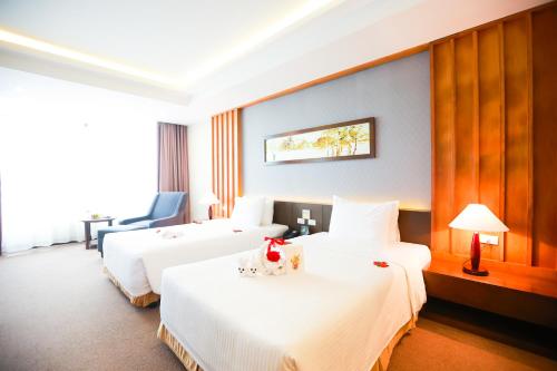 two beds in a hotel room with white sheets at Muong Thanh Luxury Nhat Le Hotel in Dong Hoi