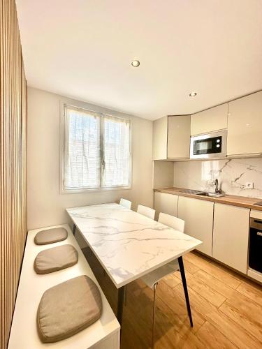 une cuisine avec une grande table blanche et un comptoir dans l'établissement Chaleureux T4, à 20 min de Paris, à Argenteuil