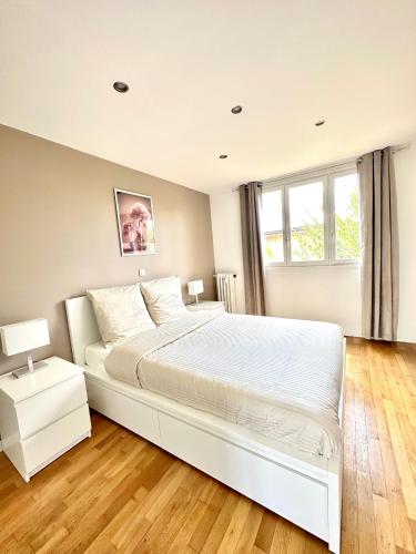 une chambre avec un grand lit blanc et une fenêtre dans l'établissement Chaleureux T4, à 20 min de Paris, à Argenteuil
