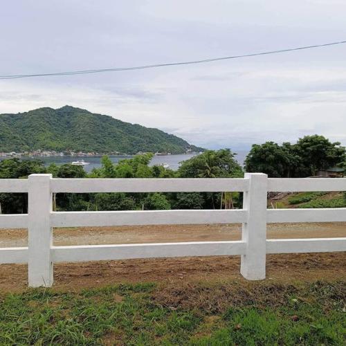 a white bench sitting on top of a field at Ocean and mountain view house in Mabini