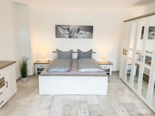 a bedroom with a large white bed with two tables at Alte Försterei 2.0 in Thale