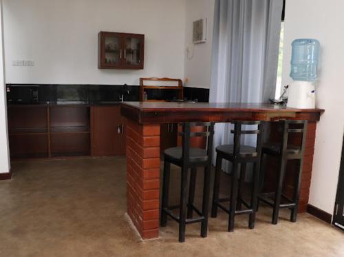 eine Backsteinbar mit Hockern in einem Zimmer mit Küche in der Unterkunft Kadupitioya Bungalow 