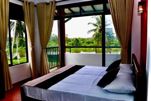 ein Schlafzimmer mit einem Bett und einem großen Fenster in der Unterkunft Kadupitioya Bungalow 