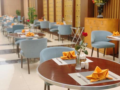 a dining room with tables and chairs with yellow napkins at Muong Thanh Luxury Nhat Le Hotel in Dong Hoi