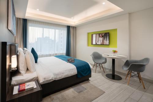 マスカットにあるCitadines Al Ghubrah Muscatのベッド、テーブル、椅子が備わるホテルルームです。