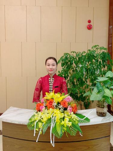 a woman standing behind a table with a bouquet of flowers at Muong Thanh Luxury Nhat Le Hotel in Dong Hoi
