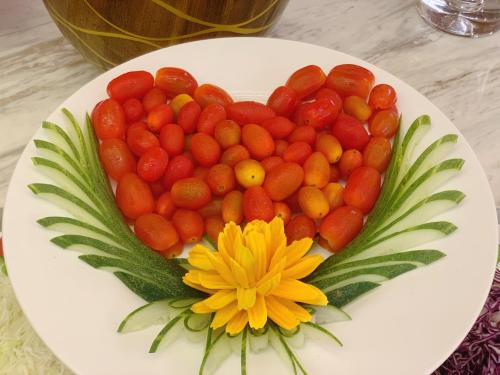 a plate of tomatoes and a flower on a table at Muong Thanh Luxury Nhat Le Hotel in Dong Hoi
