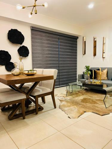 a living room with a wooden table and a dining room at Hermoso Departamento de Lujo cerca del Auditorio Telmex in Guadalajara
