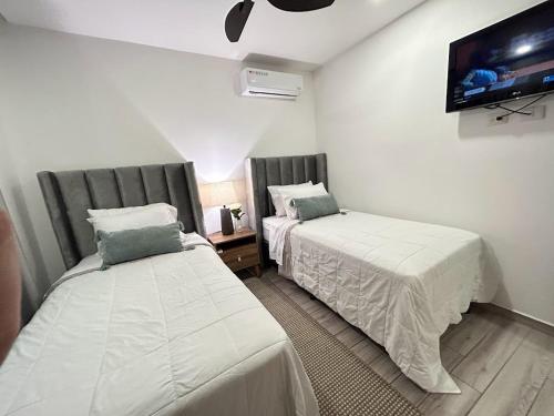 twee bedden in een kamer met een tv aan de muur bij Elegante condominio Ejecutivo familiar in San Pedro Sula