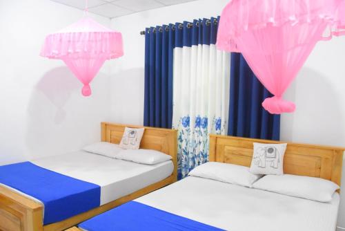 - 2 lits dans une chambre dotée de rideaux roses et bleus dans l'établissement Lion Home Stay Anuradhapura, à Anurâdhapura