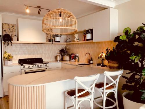 een keuken met een eiland met twee witte krukken bij Indi 500 trackside 2 Bed apartment in Gold Coast
