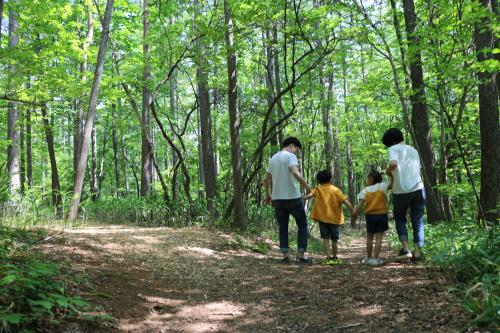 a family walking on a trail in the woods at Kusatsu Onsen Hotel Village in Kusatsu