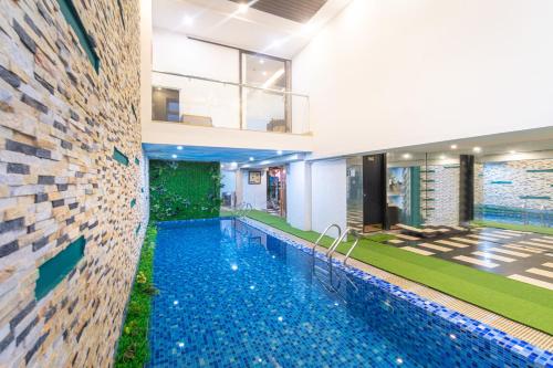 a swimming pool in a house with a brick wall at Golden Star Hotel by THG in Da Nang