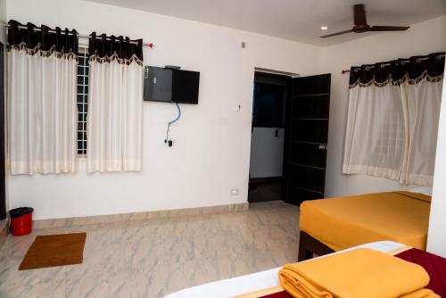 a bedroom with two beds and a tv on the wall at Hotel Sitar Grand in Tirupati
