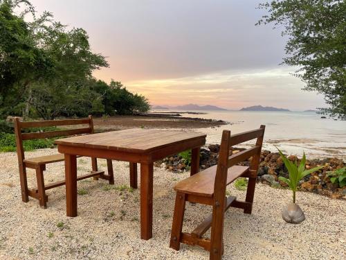 einen Holztisch und zwei Stühle am Strand in der Unterkunft Koh Mak Green View Resort in Ko Mak