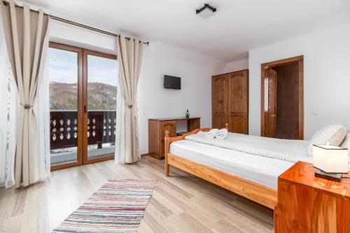 a bedroom with a bed and a large window at Pensiunea Cascada in Nemesi