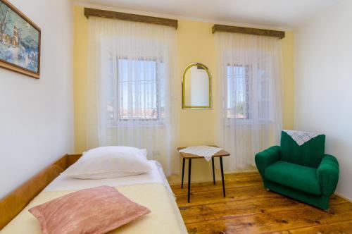 sypialnia z łóżkiem i zielonym krzesłem w obiekcie Kuca Dragica w mieście Grižane