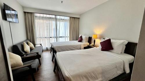 a hotel room with two beds and a chair at Rihanna service suite at times square in Kuala Lumpur