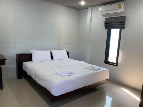 um quarto com uma cama com lençóis brancos e uma janela em ยูสีเกด รีสอร์ท em Si Sa Ket