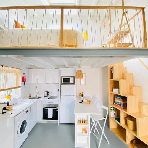 a kitchen with white appliances and a loft bed at Casa Vinte & Cinco Alojamento Local in Penha Garcia